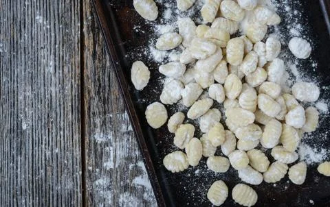 Gnocchi on cookie sheet and rustic wooden background Stock Photos