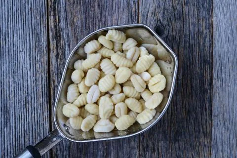 Gnocchi in strainer with rustic wood background Stock Photos