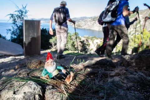 Gnome lying posing on a rock next to a landscape of cliffs by the sea and hik Foto stock