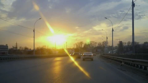 Go by car in the city against a beautiful sunset with the effect of a lens and Stock Footage
