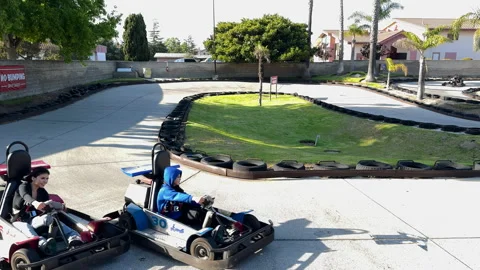 Go-kart drivers navigate a winding track lined with tires. Stock Footage 279934646