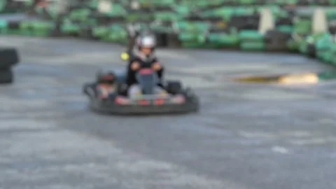 A go-kart speeding past old tire barriers on a track. 動画素材 343228880