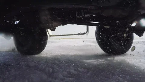 Go pro from car bottom side. View of spinning wheels driving on ice, splashes Stock Footage 104989979