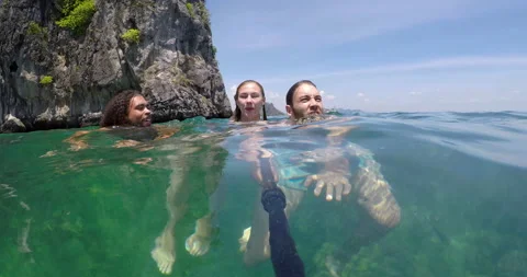 Go pro footage of young multi cultural friends swimming and taking Go pro selfie Stock Footage 201096882