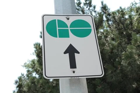 Go train vertical rectangle sign logo with arrow pointing up with trees behind Stock Photos