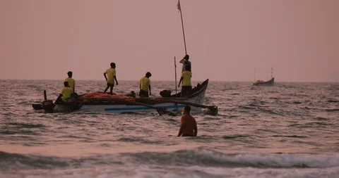 Goa, India - February 10, 2020: Fishermen In Boat Pulling Fishing Net At Sunset Stock Footage 125812200