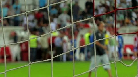 Goal net in focus,football or soccer players on play field,fans crowd on stadium Stock Footage