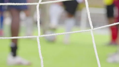 Goal net in sharp focus with football players training in background, Stock Footage 337463489