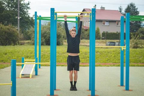 Goal-oriented blond boy builds the strength of his own body on the workout fi Stock Photos