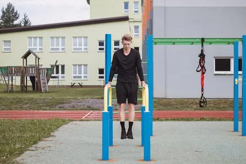 Goal-oriented blond boy builds the strength of his own body on the workout fi Stock Photos