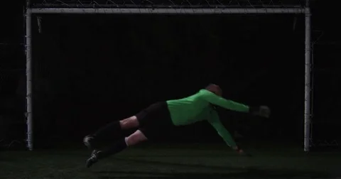 Goalie leaps to catch a ball during a night game. Stock Footage 69214533