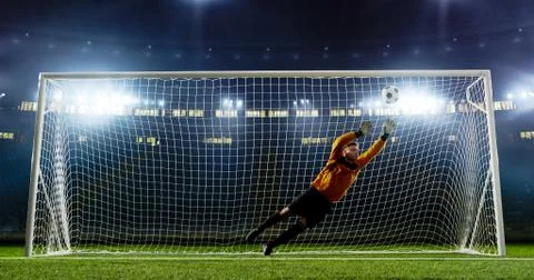 Goalkeeper is trying to save from a goal on an empty soccer stad Stock Photos