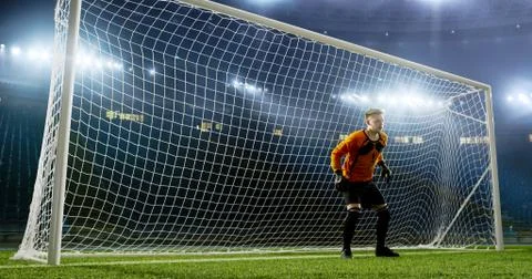 Goalkeeper is trying to save from a goal on an empty soccer stad Stock Photos