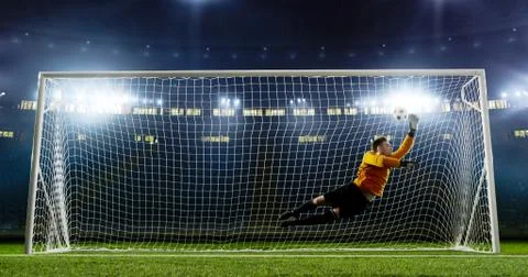 Goalkeeper is trying to save from a goal on an empty soccer stad Stock Photos