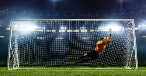 Goalkeeper is trying to save from a goal on an empty soccer stad Stock Photos