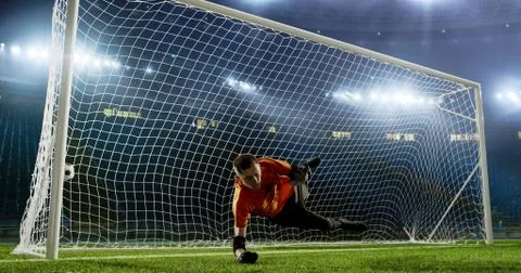 Goalkeeper is trying to save from a goal on an empty soccer stad Stock Photos
