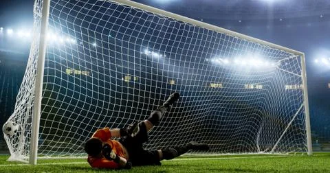 Goalkeeper is trying to save from a goal on an empty soccer stad Stock Photos