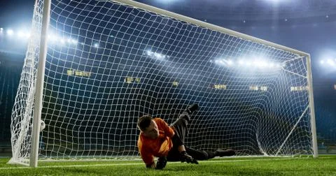 Goalkeeper is trying to save from a goal on an empty soccer stad Stock Photos