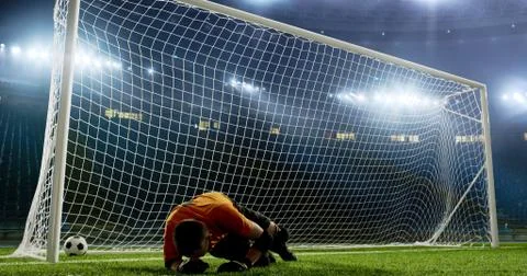 Goalkeeper is trying to save from a goal on an empty soccer stad Stock Photos