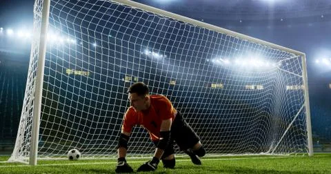 Goalkeeper is trying to save from a goal on an empty soccer stad Stock Photos