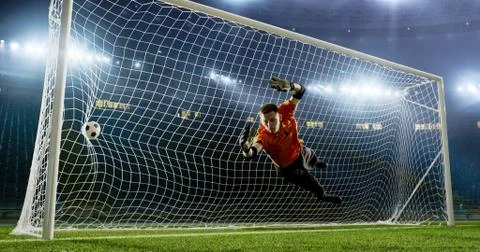 Goalkeeper is trying to save from a goal on an empty soccer stad Stock Photos