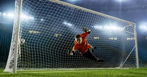 Goalkeeper is trying to save from a goal on an empty soccer stad Stock Photos