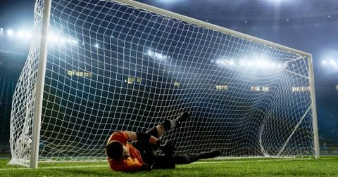 Goalkeeper is trying to save from a goal on an empty soccer stad Stock Photos