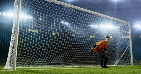 Goalkeeper is trying to save from a goal on an empty soccer stad Stock Photos