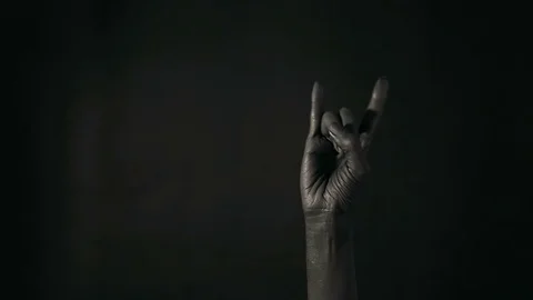 Goat gesture on a dark background. Black hand doing rock symbol. Hands up at  Stock Footage 100681242