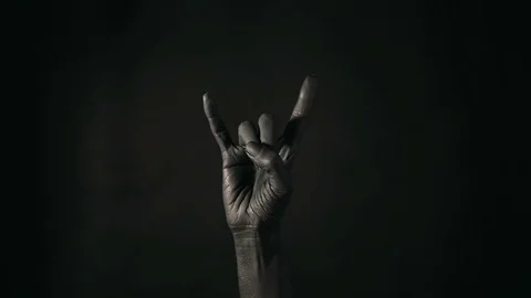Goat gesture on a dark background. Black hand doing rock symbol. Hands up at  Stock Footage 100681243