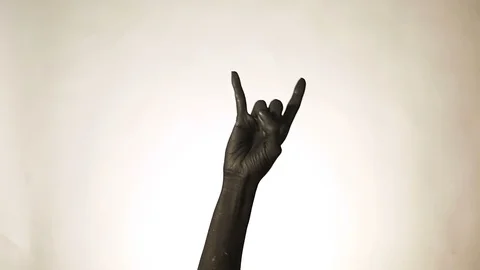 Goat gesture on a dark background. Black hand doing rock symbol. Hands up at  Stock Footage 100681382