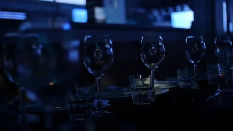 Goblets and shot glasses with liquid stand on black bar Stock Footage 108583343