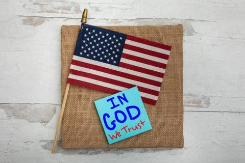 In God we trust on posted note sitting on American flag background Stock Photos