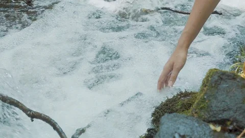 Goddess of forest holds her hand along swirling and fast river, checks its cold Stock Footage 106522906