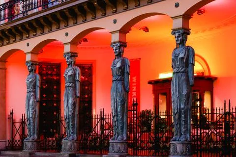Goddess statues of a classical building facade lit at night Stock Photos