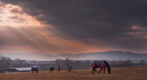 Godrays cuting hole in to the Stormy clouds over the horse stable Foto stock