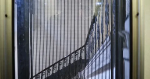 Going down in a vintage elevator past a historic building's staircase Stock Footage 336048890