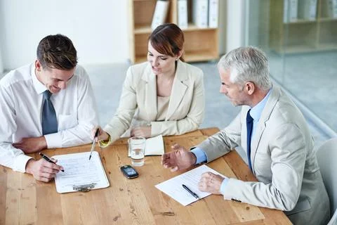 Going through paperwork. a group of colleagues having a meeting in the boardroom Photos