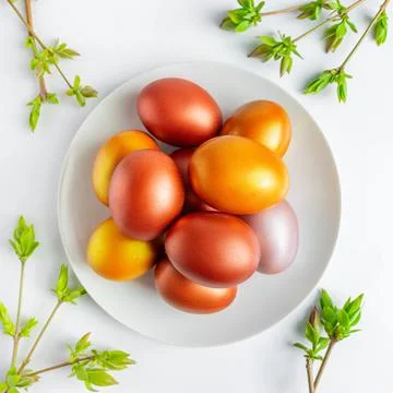 Gold and bronze Easter eggs on white background. Green buds of willow Stock Photos
