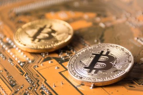 Gold and silver Bitcoins on a computer motherboard with shallow depth of fiel Stock Photos