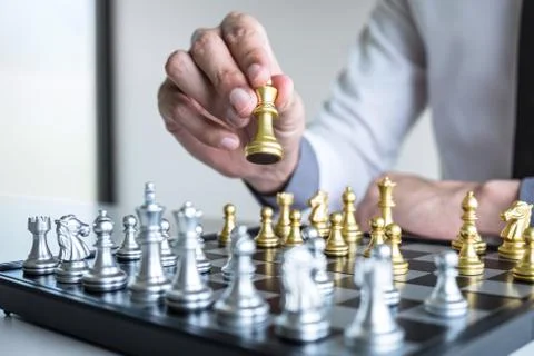 Gold and silver chess with player, Hands of businessman moving chess figure i Stock Photos