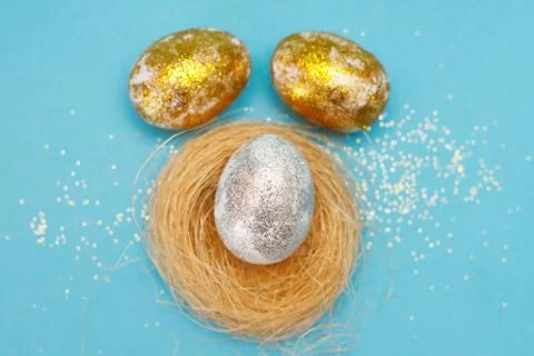 Gold and silver Easter eggs with nest on a blue background. Easter concept. H Stock Photos