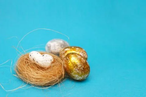 Gold and silver Easter eggs with nest on a blue background. Easter concept. H Stockfoto's