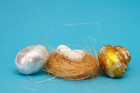 Gold and silver Easter eggs with nest on a blue background. Easter concept. H 스톡 사진