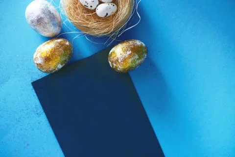 Gold and silver Easter eggs with nest on a blue background. Easter concept. H 스톡 사진