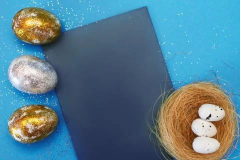 Gold and silver Easter eggs with nest on a blue background. Easter concept. H Фото