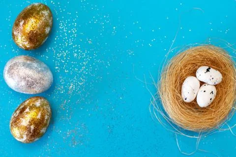 Gold and silver Easter eggs with nest on a blue background. Easter concept. H Stock-Fotos