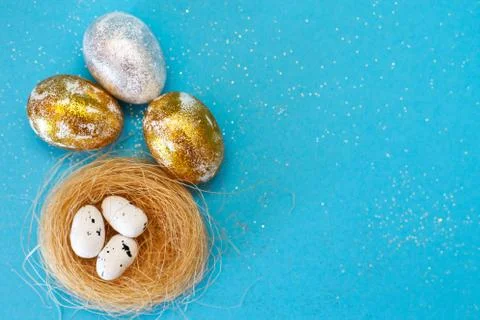Gold and silver Easter eggs with nest on a blue background. Easter concept. H Stock Photos