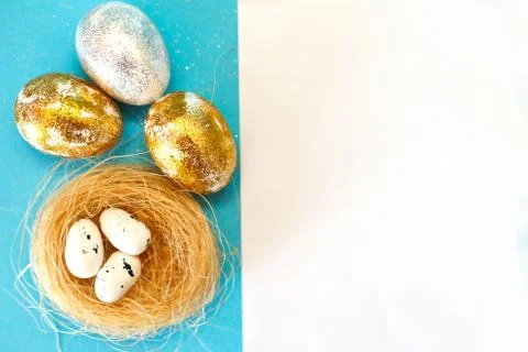 Gold and silver Easter eggs with nest on a blue background. Easter concept. H 스톡 사진
