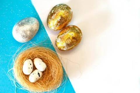 Gold and silver Easter eggs with nest on a blue background. Easter concept. H Foto stock